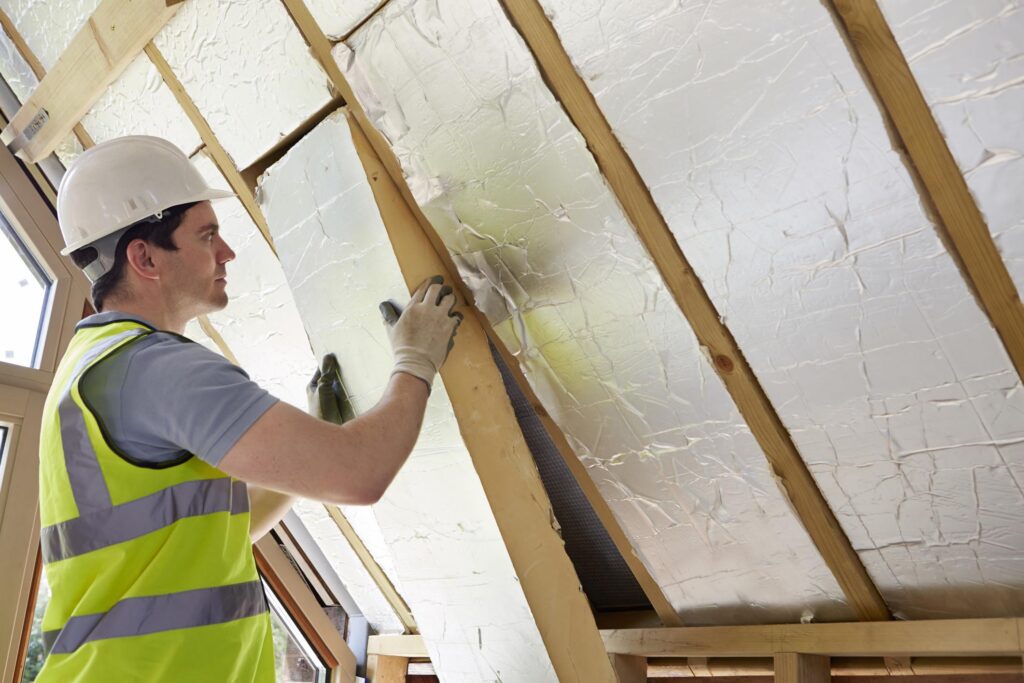 a man in a hard hat and safety vest working on a wall