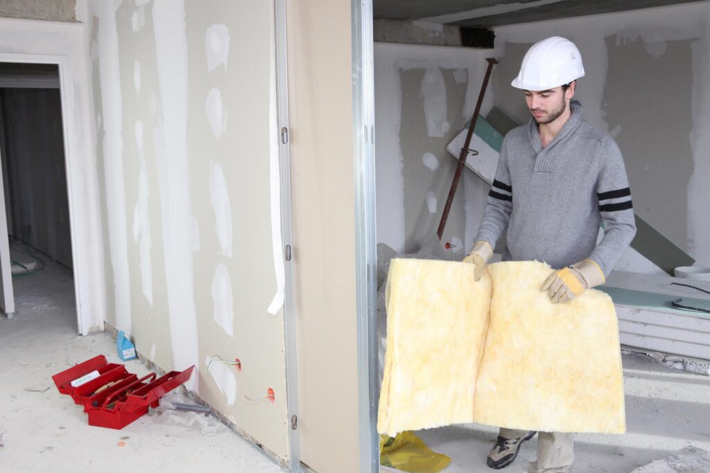 a man in a white hard hat holding a piece of insulation